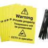 Warning private property trespassers will be prosecuted CCTV in operation signs with drilled holes and cable ties. yellow background with black text and symbols
