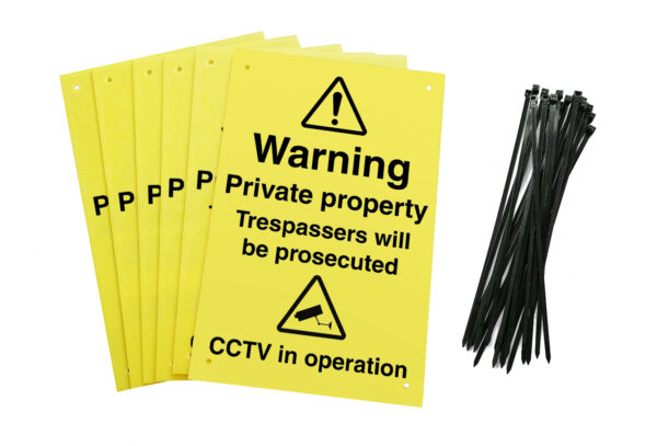 Warning private property trespassers will be prosecuted CCTV in operation signs with drilled holes and cable ties. yellow background with black text and symbols