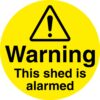warning this shed is alarmed safety security sign. 100mm diameter circle self adhesive. yellow background with black text and symbol
